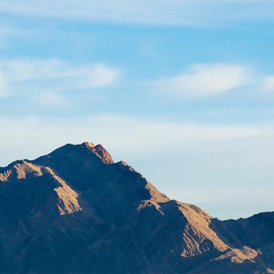 A mountain landscape with sun and shadows against a blue sky